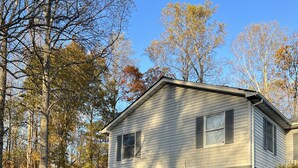 A two-story house with a front porch, a small deck, and a yard with trees and grass. - Cozy 1BR Apt Minutes From Skyline Drive!! (Amissville)