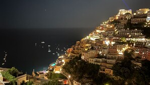 A coastal town at night with buildings illuminated, a moon in the sky, and boats on the water. - Palazzo Vittoria with wonderful terrace & Jacuzzi (Campania)