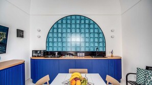 A modern kitchen with a blue countertop, a microwave, and a sink. There is a fruit bowl on the dining table. - Palazzo Vittoria with wonderful terrace & Jacuzzi (Campania)