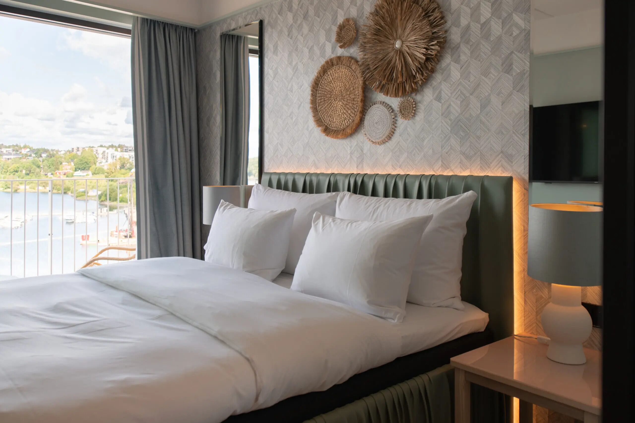 Ein Hotelzimmer mit einem großen Bett, Blick auf die Stadt und Wandgestaltung.
