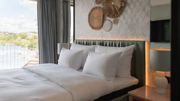 Ein Hotelzimmer mit einem großen Bett, Blick auf die Stadt und Wandgestaltung.