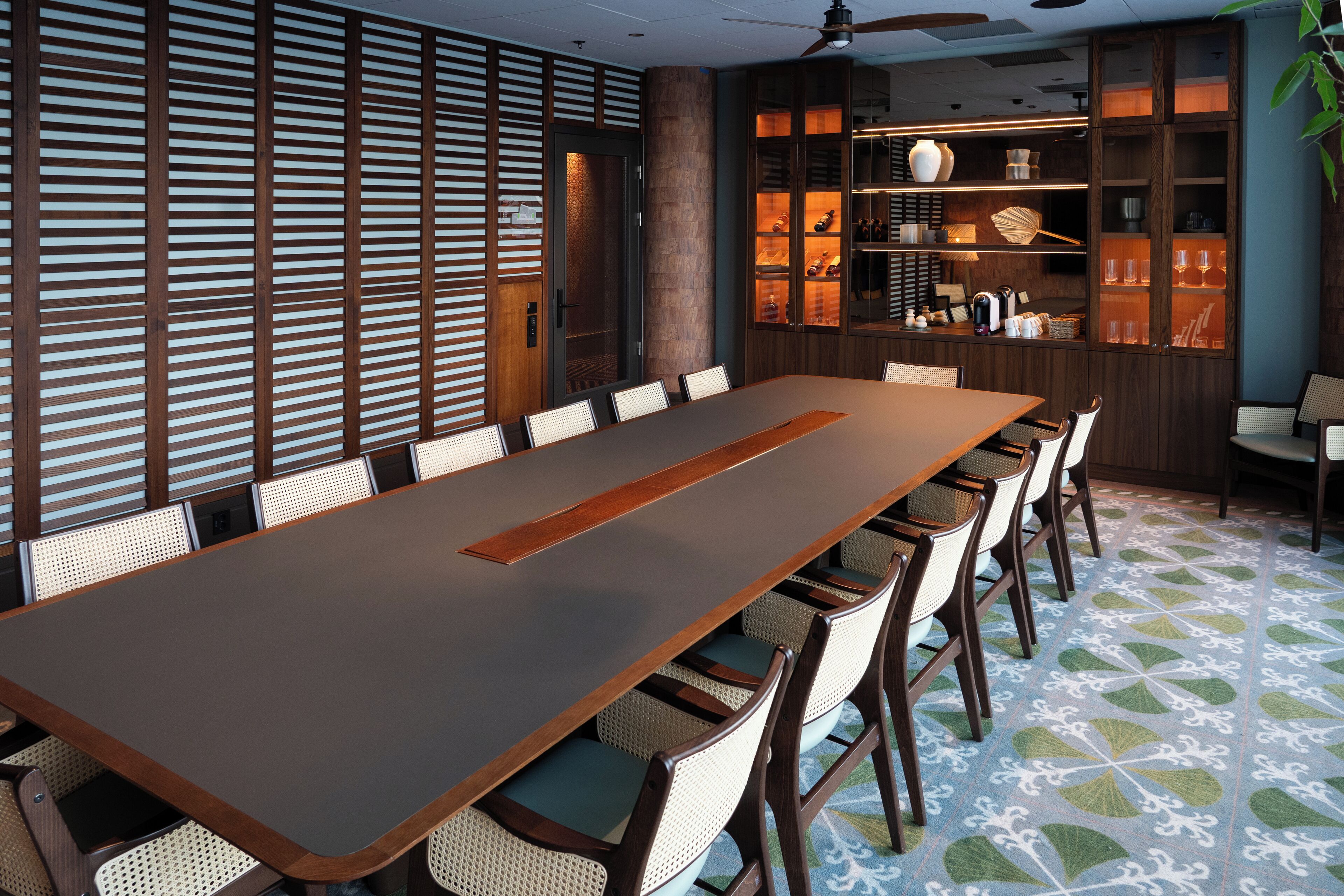 A conference room with a long table, chairs, and a cabinet with shelves.