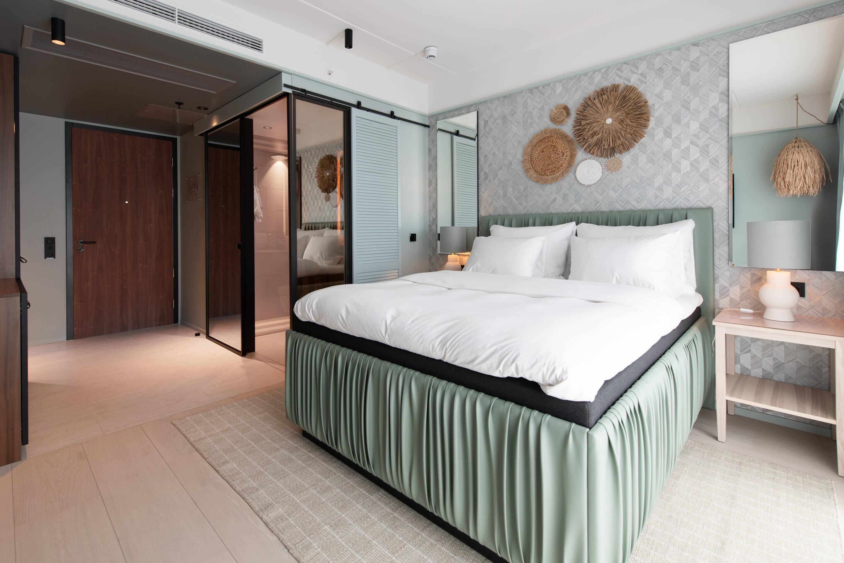A modern bedroom with a large bed, a sliding door closet, and a wall-mounted mirror.