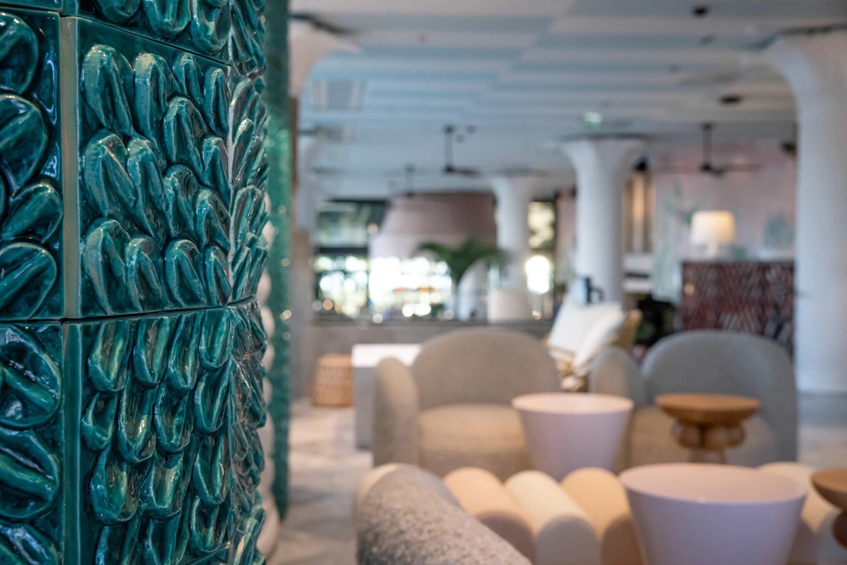 Un interior moderno con una pared texturizada color turquesa, asientos cómodos y una zona de bar.