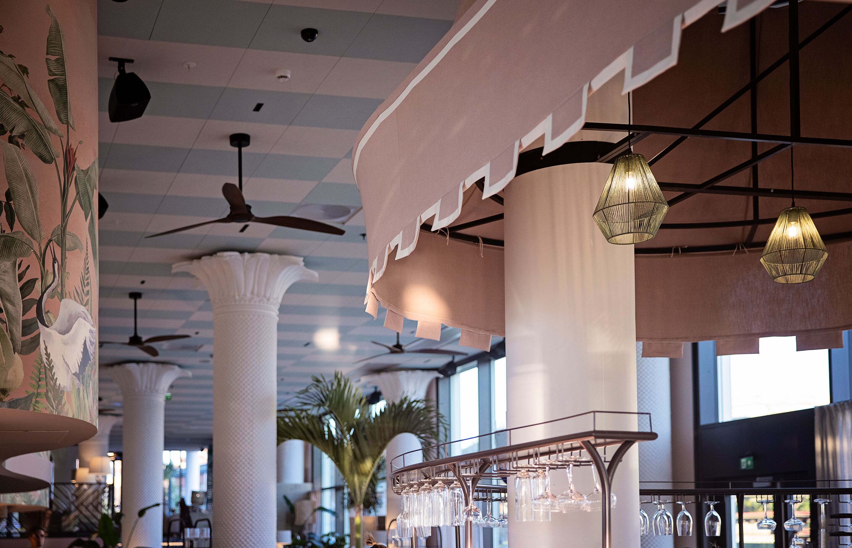 Een ruim interieur met hoge plafonds, grote kolommen en hangende pendelverlichting.