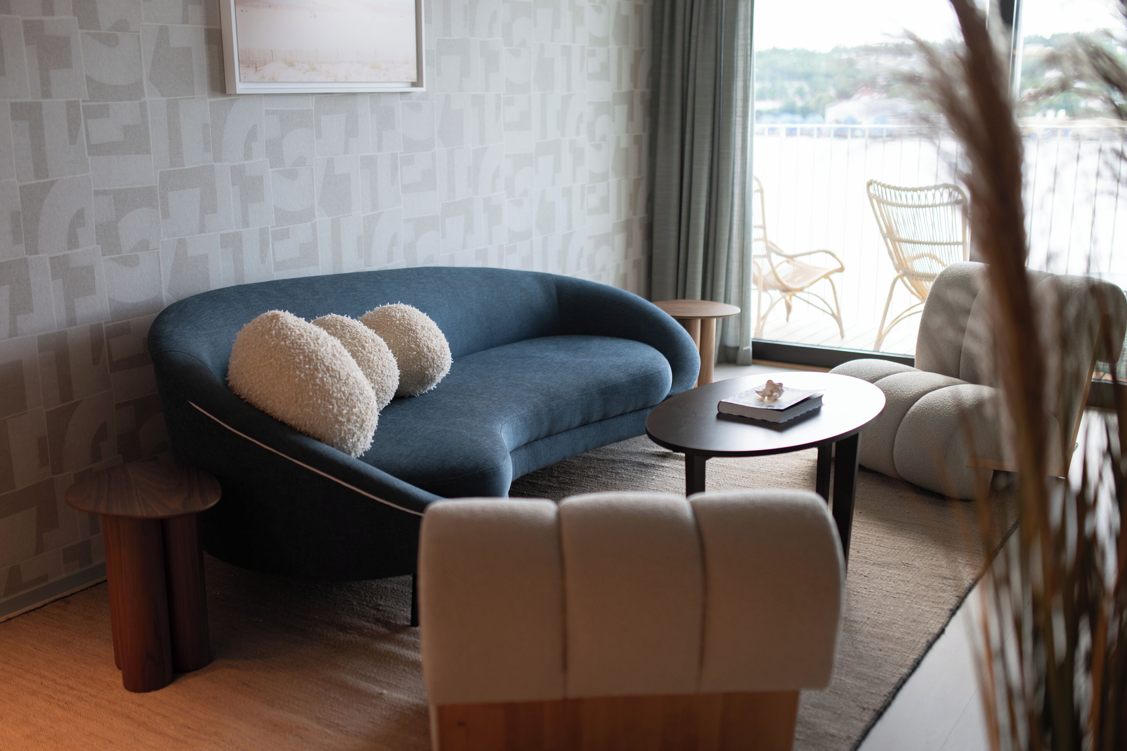 Una sala de estar moderna con un sofá azul, una mesa de centro redonda y un sillón blanco.