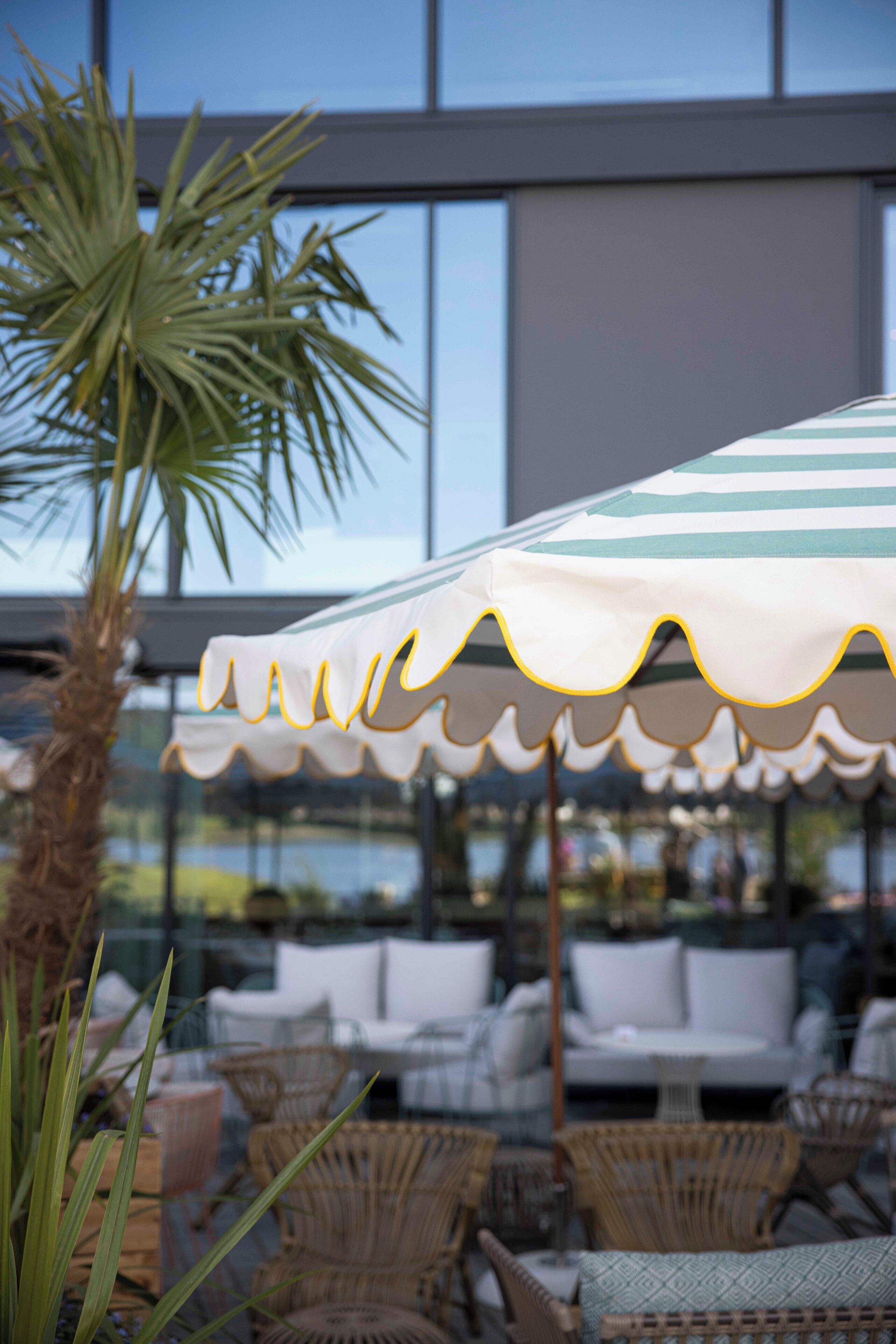 An outdoor seating area with wicker furniture and a striped umbrella.
