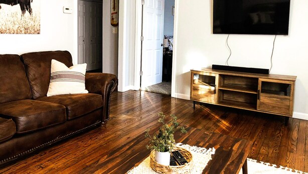 A living room with a brown leather sofa, a wooden entertainment unit, and a mounted TV. - Minutes from the Ark Encounter! (Dry Ridge)