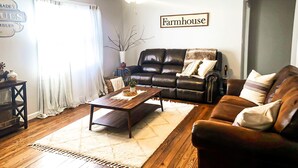 A living room with a black leather sofa, a wooden coffee table, a ceiling fan, and a sign that reads "Farmhouse". - Minutes from the Ark Encounter! (Dry Ridge)