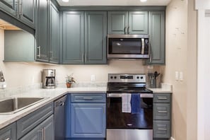 Uma cozinha com armários escuros, micro-ondas, forno e cafeteira.