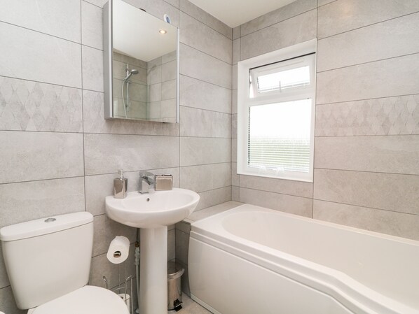 A modern bathroom with a toilet, sink, and bathtub. - Woodpecker Lodge (Beaworthy)