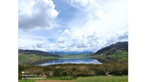 Un paisaje tranquilo con un lago, colinas y un cielo nublado.