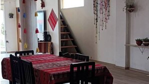 Un comedor con una mesa dispuesta para cuatro personas, una escalera y una pared decorada.