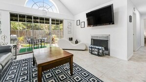 Un salón amplio con un ventanal grande, una chimenea y un televisor de pantalla plana montado en la pared.