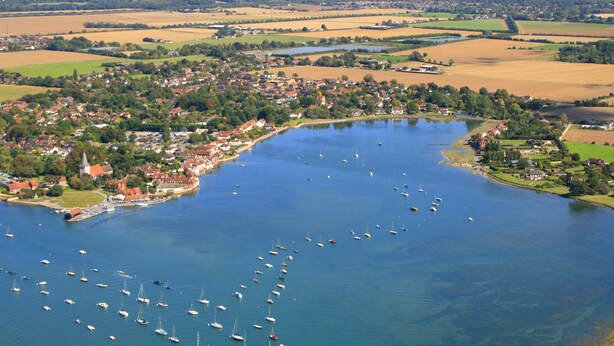 An aerial view of a lakeside town with numerous boats, a church, and surrounding fields. - Spacious Refurbished Apartment - 2 mins walk from Bosham Harbour (Bosham)
