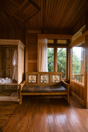 Una cabaña de madera con un banco, un armario de madera y una ventana con cortinas.