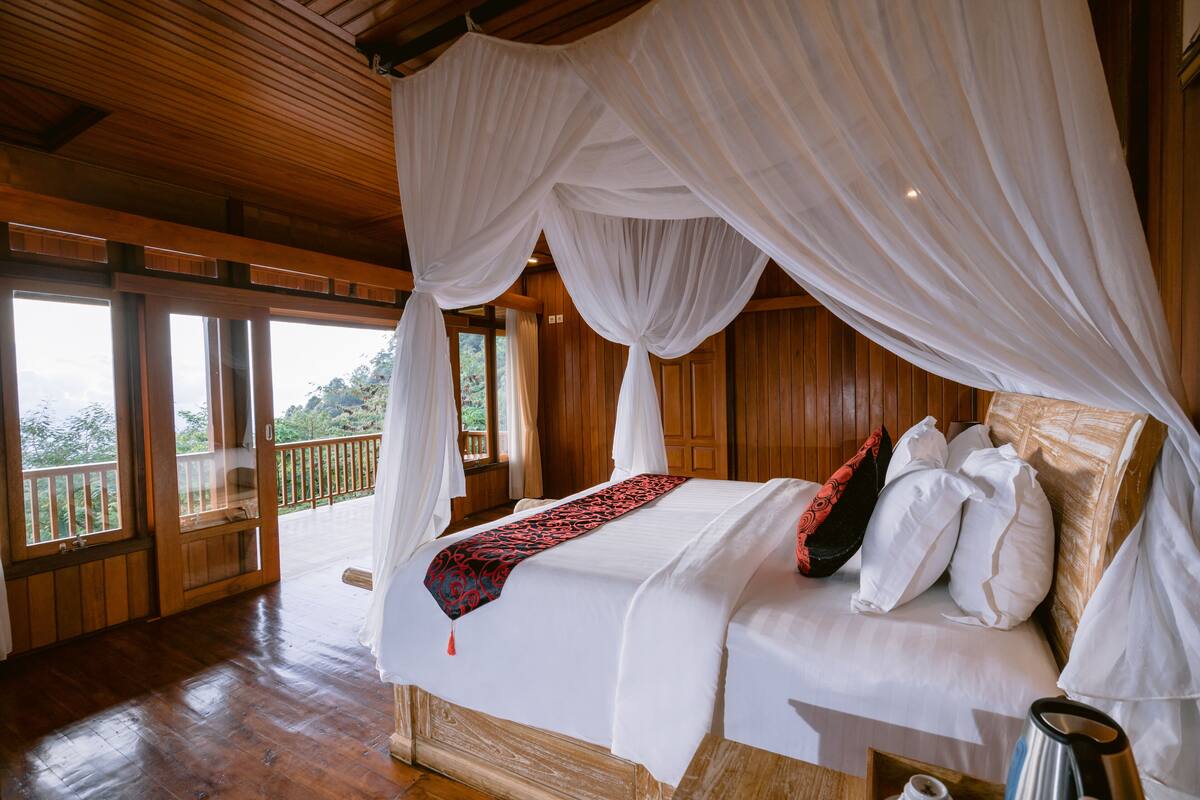 A large bed with a canopy, wooden walls, and a balcony with a railing.