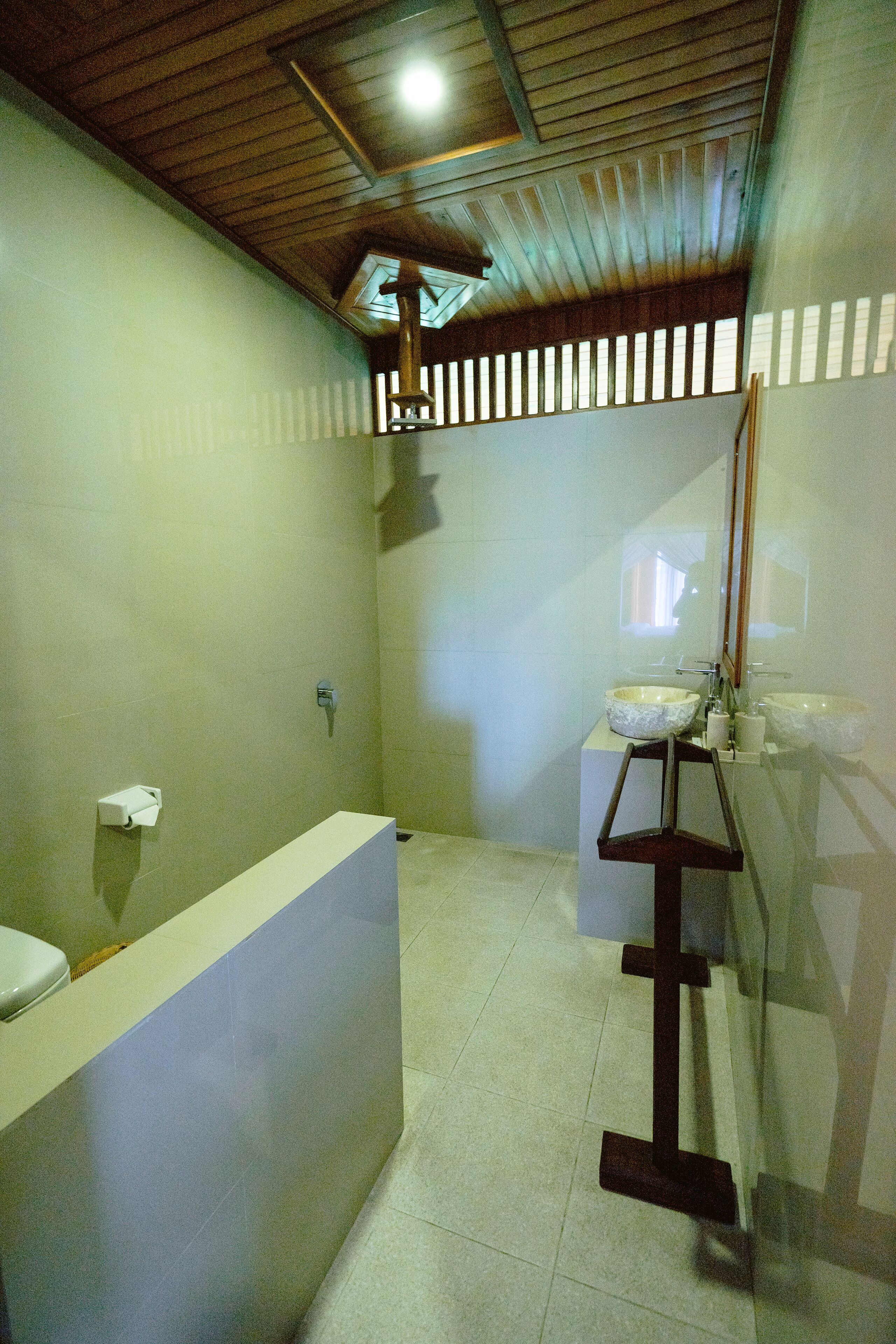 A bathroom with a wooden ceiling, a white sink, and a mirror.