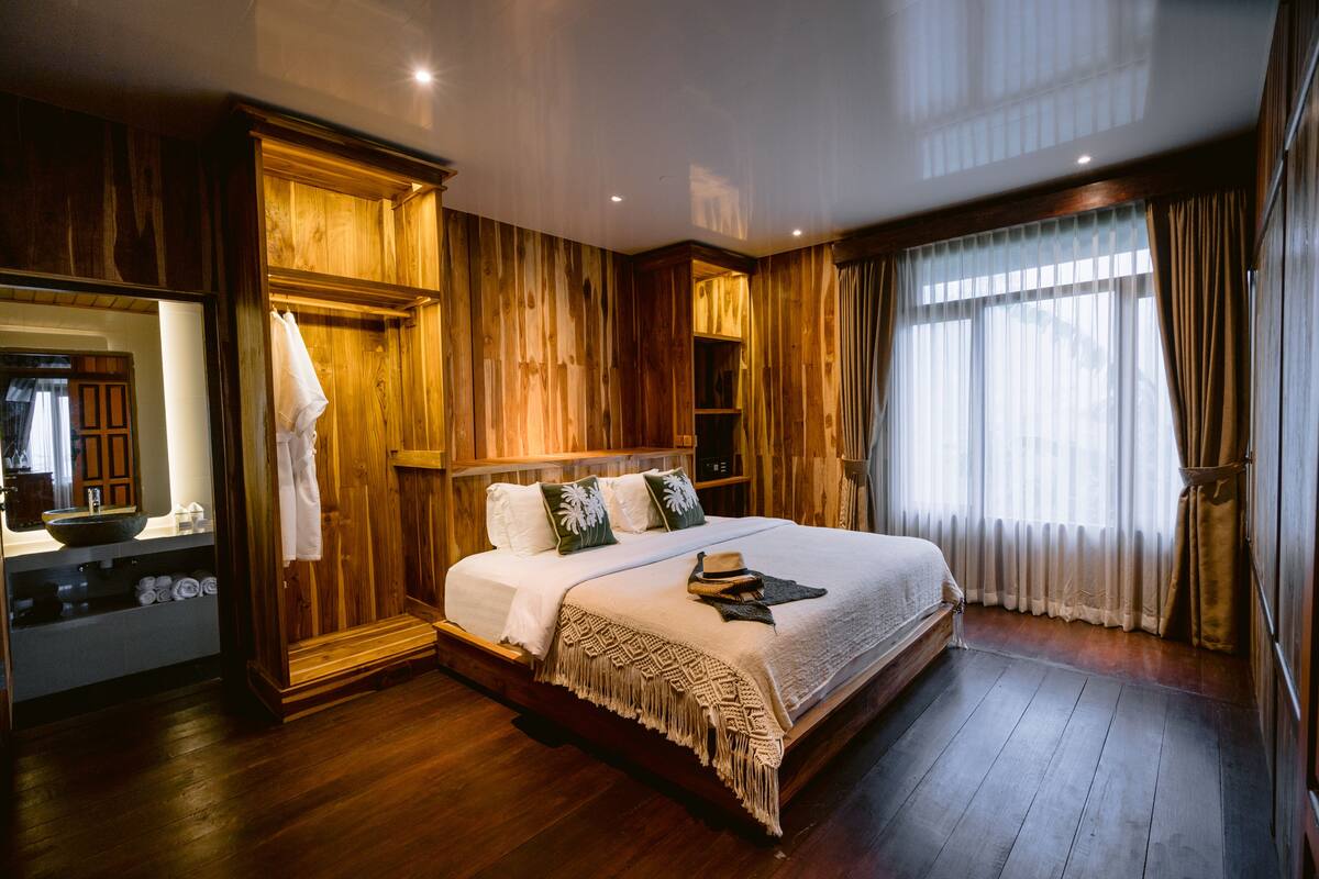 A large bed with a wooden headboard, a bedside table, and a mirror.