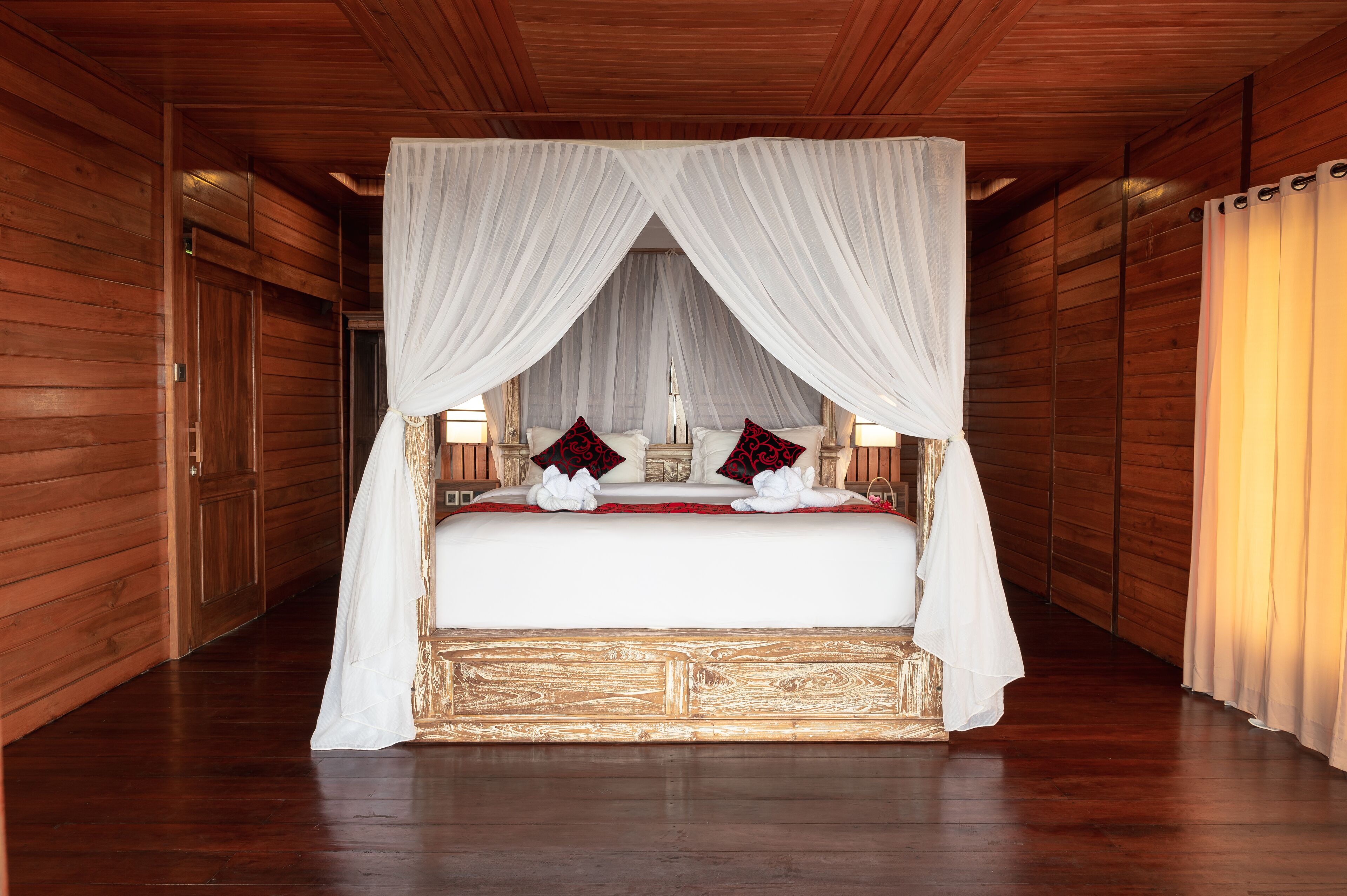 Una stanza in legno con un letto a baldacchino, pareti e pavimento anch'essi in legno.