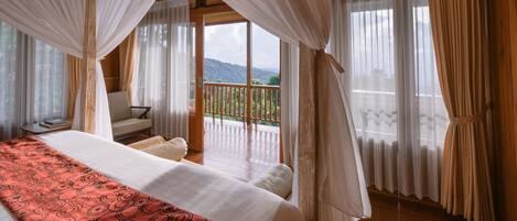 A bedroom with a large bed, a balcony, and a view of the mountains.