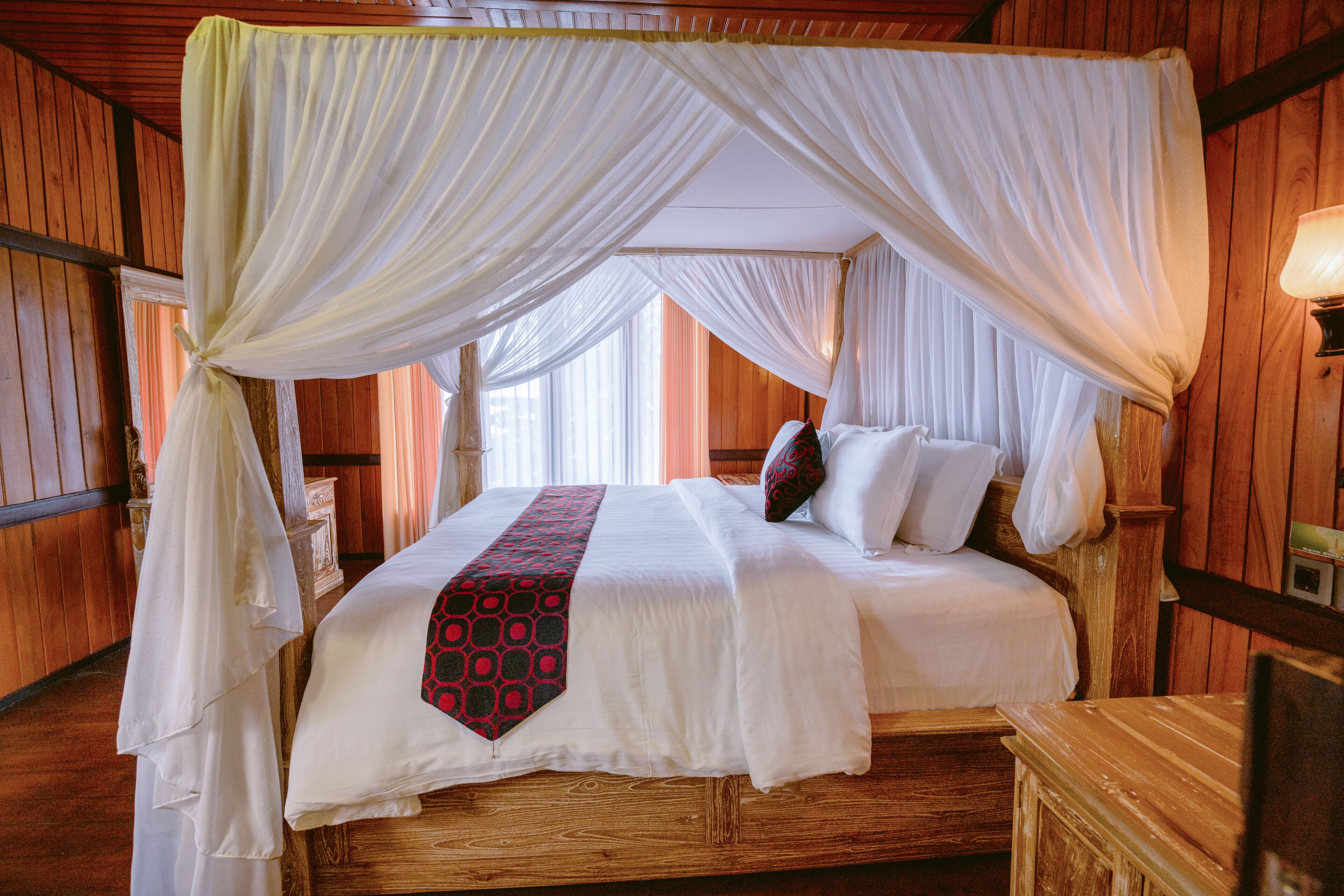 A bed with a canopy, wooden walls, and a bedside table.