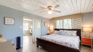 A bedroom with a large bed, a ceiling fan, and a nightstand with a lamp. - Beautiful downtown Melbourne Beach renovated apartment one block from the beach! (Melbourne Beach)