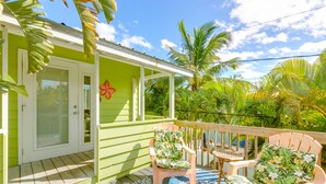 A green house with a porch, two wooden chairs with floral upholstery, and a blue patterned rug. - Beautiful downtown Melbourne Beach renovated apartment one block from the beach! (Melbourne Beach)