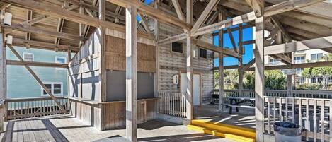 A wooden deck with a view of a building and a clear sky.