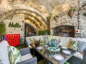 An outdoor dining area with a brick wall, arched ceiling, and a 'Hello' sign.