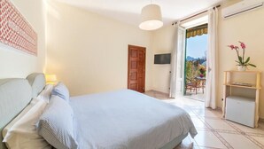 Un dormitorio con cama, televisión, puerta y balcón con mesa y sillas.