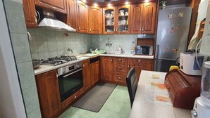 A kitchen with wooden cabinets, a stove, oven, microwave, and a blender.