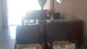 Ein Wohnzimmer mit zwei Holzdavanzsofas, einem Glastisch und einer Vase mit Blumen.