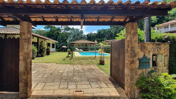 Ein Steingewölbe führt zu einem Poolbereich mit einer Pergola darüber.