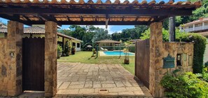 Un arco de piedra que da acceso a una zona de piscina con una pérgola.