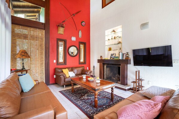 A living room with a brown leather sofa, a wooden coffee table, and a red accent wall.