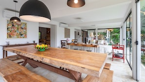 Cocina amplia con una isla grande de madera, iluminación colgante y vistas al exterior a través de ventanas grandes.