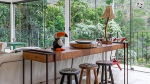 Una cocina moderna con un ventanal grande, una mesa de madera, taburetes y una lámpara decorativa.