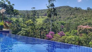 Una piscina con vistas a un paisaje verde exuberante y colinas al fondo.