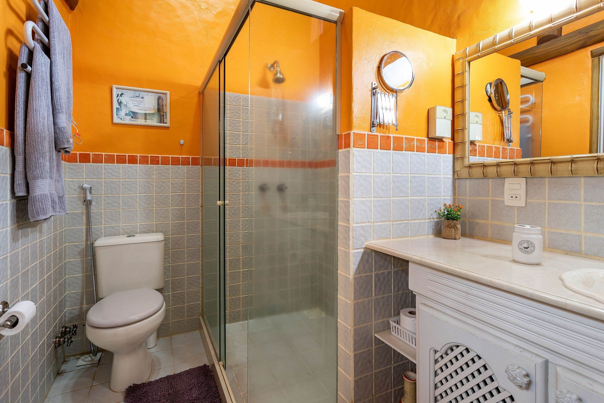 Une salle de bain avec une douche à parois de verre, des toilettes, un lavabo avec un miroir et un porte-serviettes.