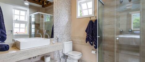 A modern bathroom with a large mirror, a white sink, a toilet, and a glass-enclosed shower.