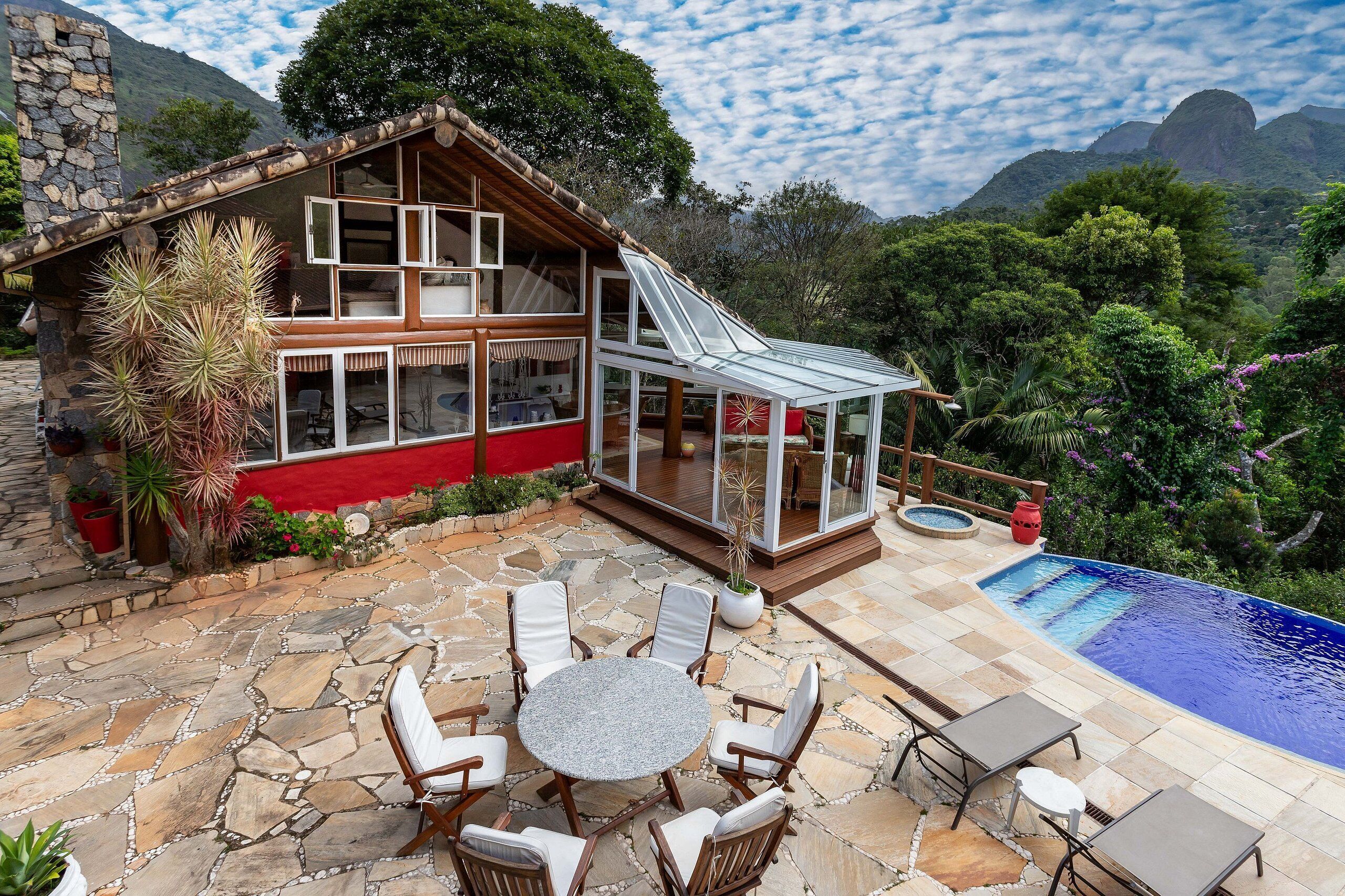 Ein Haus mit Natursteinfassade, einer gläsernen Veranda und einem Schwimmbad.