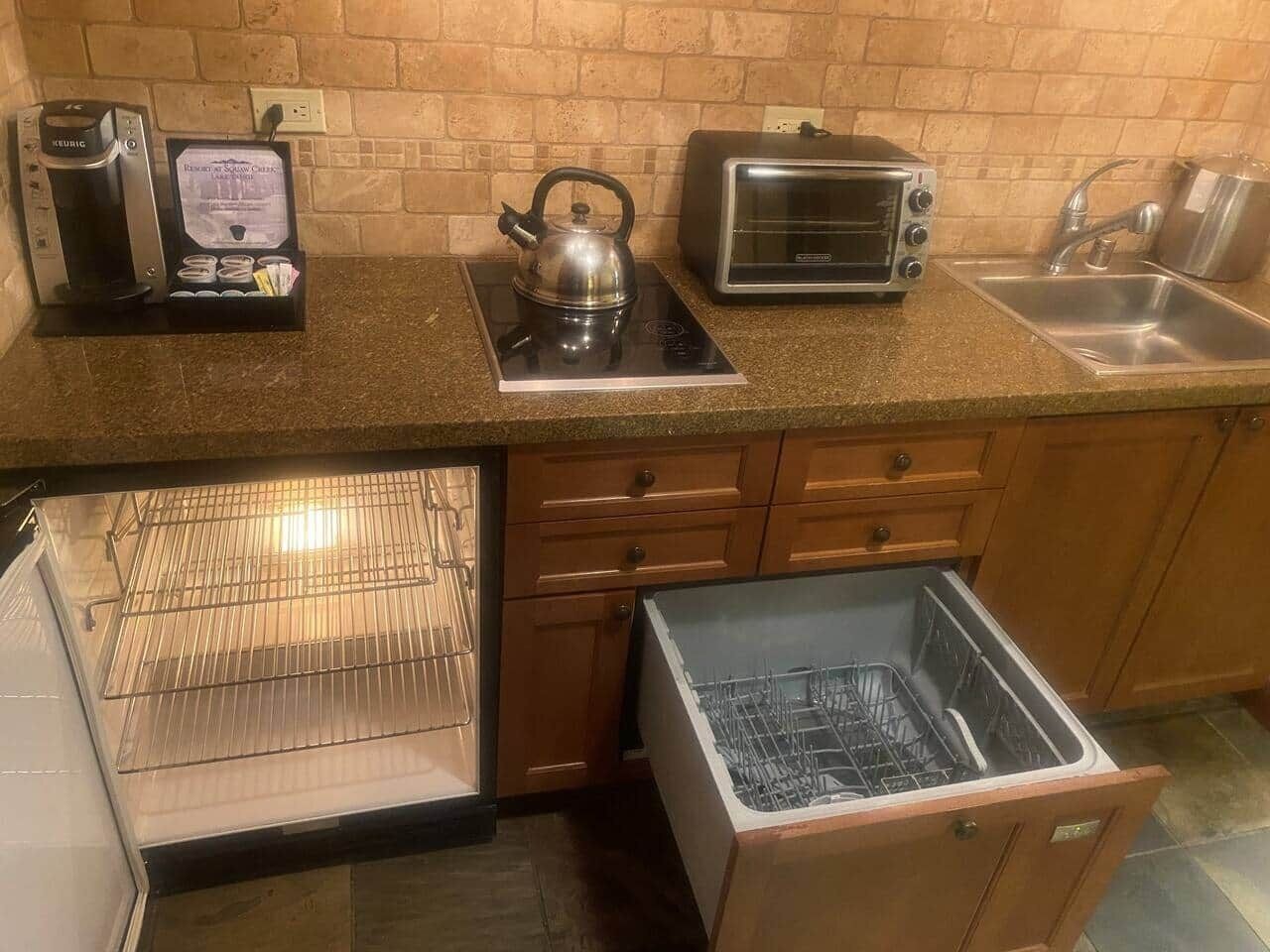 A compact kitchen with a built-in oven, a kettle, a toaster, and a sink.