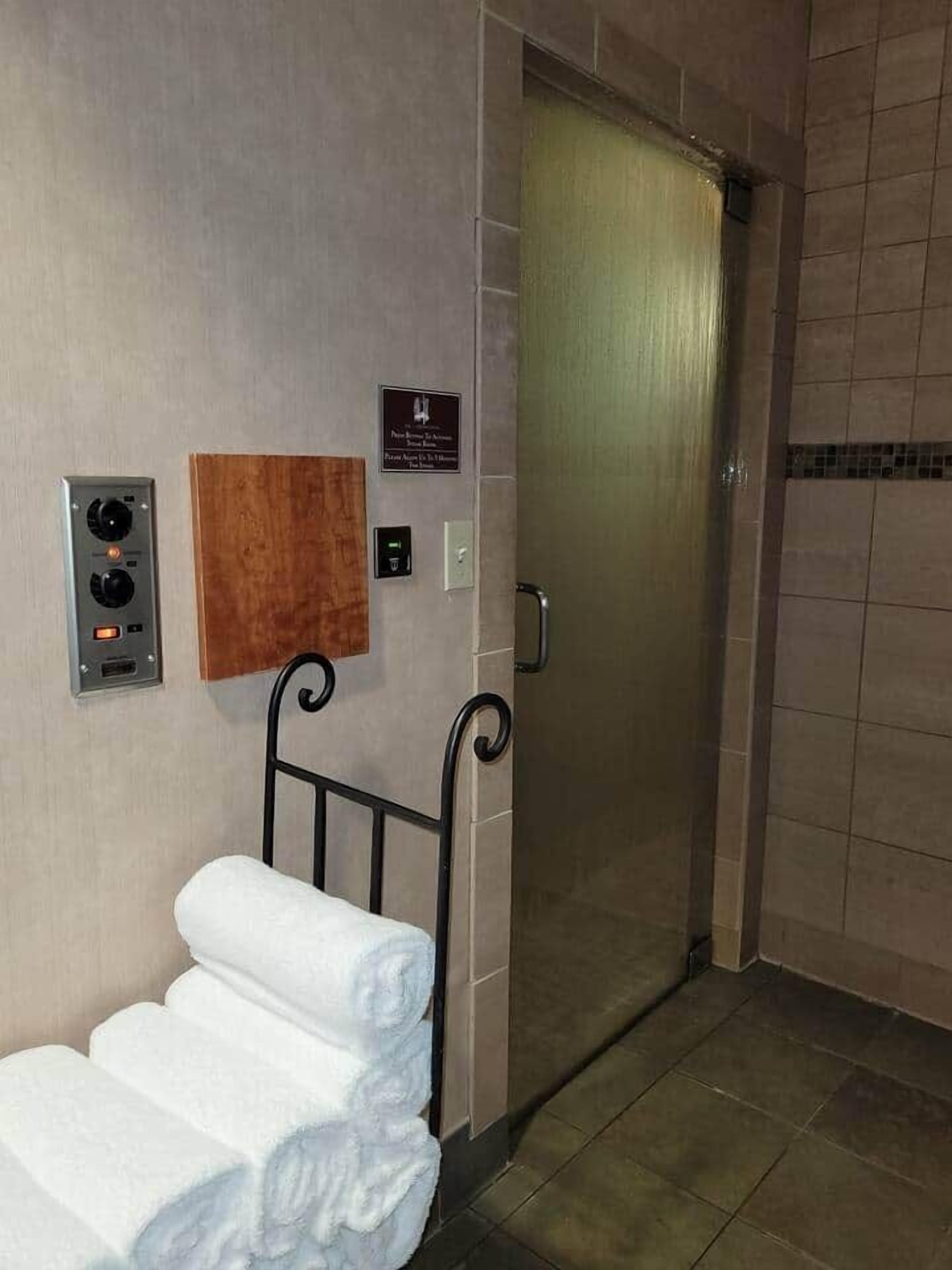 Een hotel lift met bedieningspaneel, handdoekhouder en een bord aan de muur.