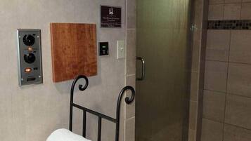 Een hotel lift met bedieningspaneel, handdoekhouder en een bord aan de muur.