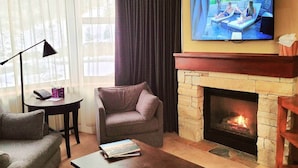 A living room with a fireplace, a sofa, a coffee table, and a TV mounted on the wall.