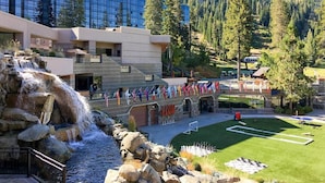 A hotel with a waterfall feature, a pool, and a well-maintained lawn.