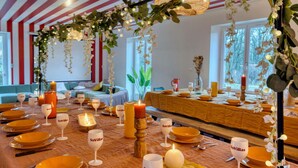 Un espace repas avec des tables dressées pour le repas, agrémenté d’un plafond à rayures et de décorations florales suspendues.