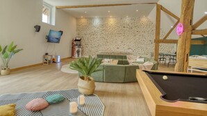 A cozy living room with a pool table, a green sofa, and a stone-patterned wall. - So Villa Chasseuserie (89) - Heated pool - Foot - 2h Paris - 45p. (Auxerre)