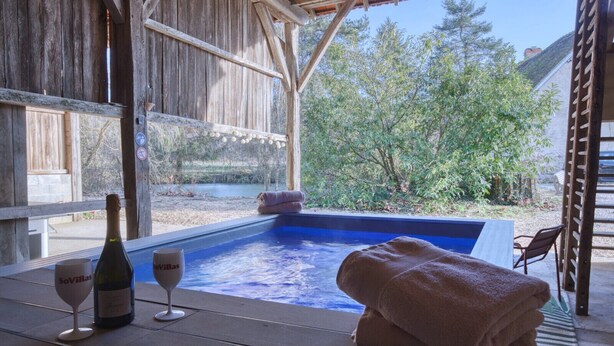 A wooden deck with a hot tub, towels, and a bottle of wine. - So Villa Chasseuserie (89) - Heated pool - Foot - 2h Paris - 45p. (Auxerre)